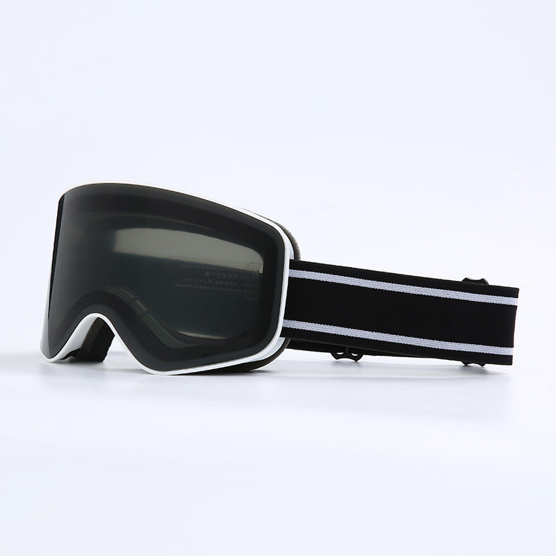Black ski goggles with a black and white striped strap on a light gray background