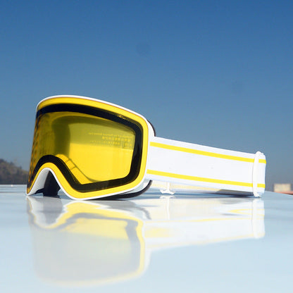 Yellow goggles with white frame on a reflective surface with blue sky background