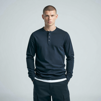 Man wearing a navy long-sleeve henley shirt and dark pants on a light gray background