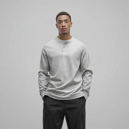 Man wearing a light gray long-sleeve shirt and dark pants against a plain background