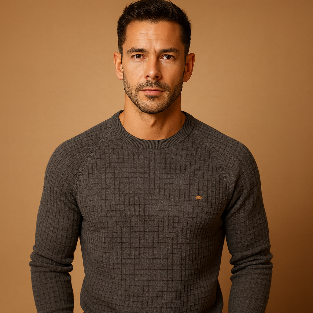 Man wearing a dark grey textured sweater against a brown background