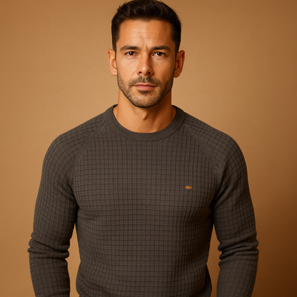 Man wearing a dark grey textured sweater against a brown background