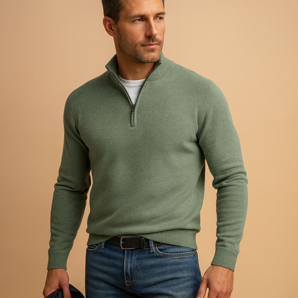Man wearing a green quarter-zip sweater and blue jeans against a beige background