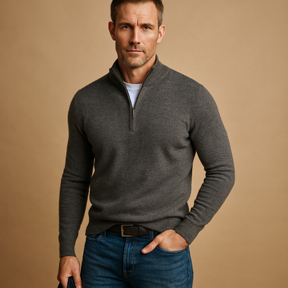 Man wearing a grey sweater and blue jeans against a beige background